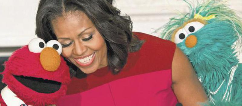 Michelle Obama saluda a Elmo y Rosita, personajes de 'Plaza Sésamo'. Foto: Saul Loeb / AFP