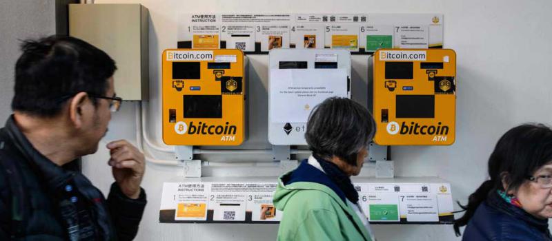 En Hong Kong unos traseuntes se pasean junto a unas máquinas de ATM en donde se obtiene Bitcoins. Foto: AFP
