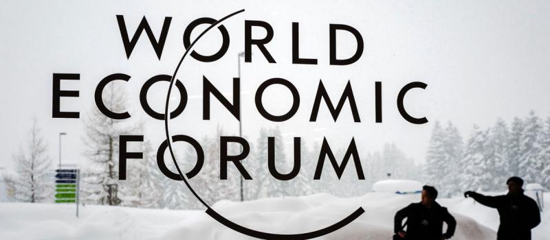 En esta foto de archivo, tomada el 22 de enero de 2018, un guardia de seguridad muestra el camino a un hombre que se encuentra fuera del Centro de Congresos de Davos bajo la nieve antes de la apertura de la reunión anual del Foro Económico Mundial (WEF).