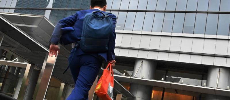 Un empleado de una firma tecnológica china ingresa corriendo al edificio donde trabaja, en Shanghái.