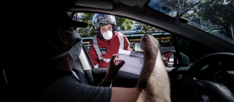 Una persona le muestra los documentos a una policía en un control de circulación, en Buenos Aires