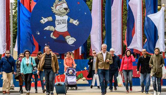 Personas caminan por una calle de Moscú, decorada por motivo del Mundial de Fútbol que empieza el 14 de junio. Resalta la imagen de la mascota Zabivaka. Foto: Mladen Antonov / AFP