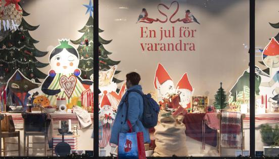 Una mujer camina frente a la vitrina de una tienda decorada por Navidad, en Estocolmo, capital de Suecia. Foto: Fredrik Sandberg /EFE